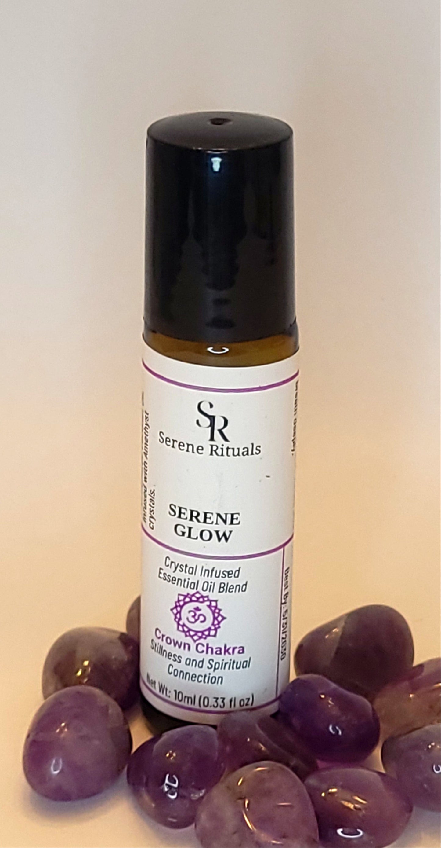 Roll-on bottle of essential oil with Amethyst crystals in the background.
