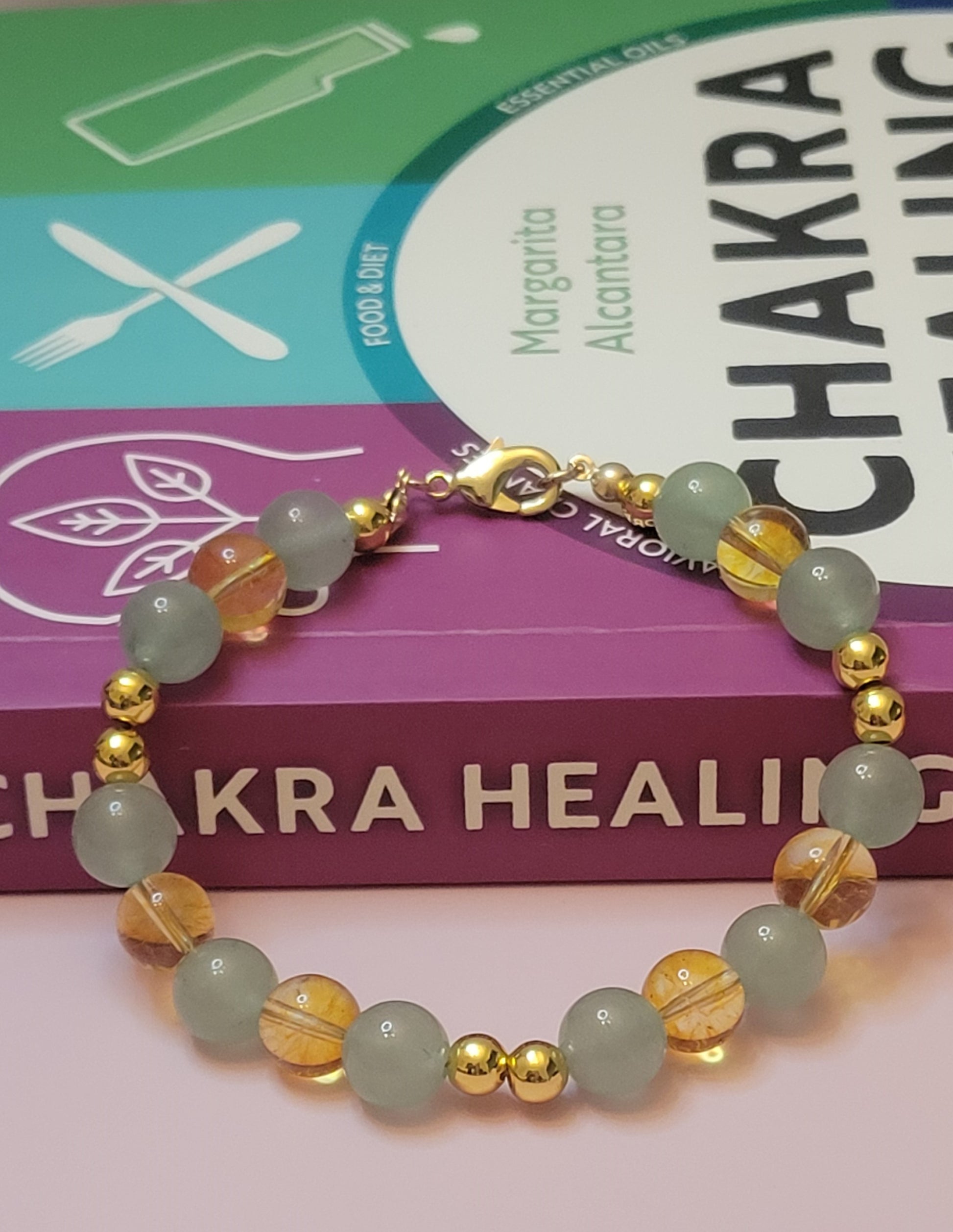 Abundant Glow Bracelet with Green Aventurine and Yellow Citrine gemstone beads and gold accents on a book titled 'Chakra Healing'