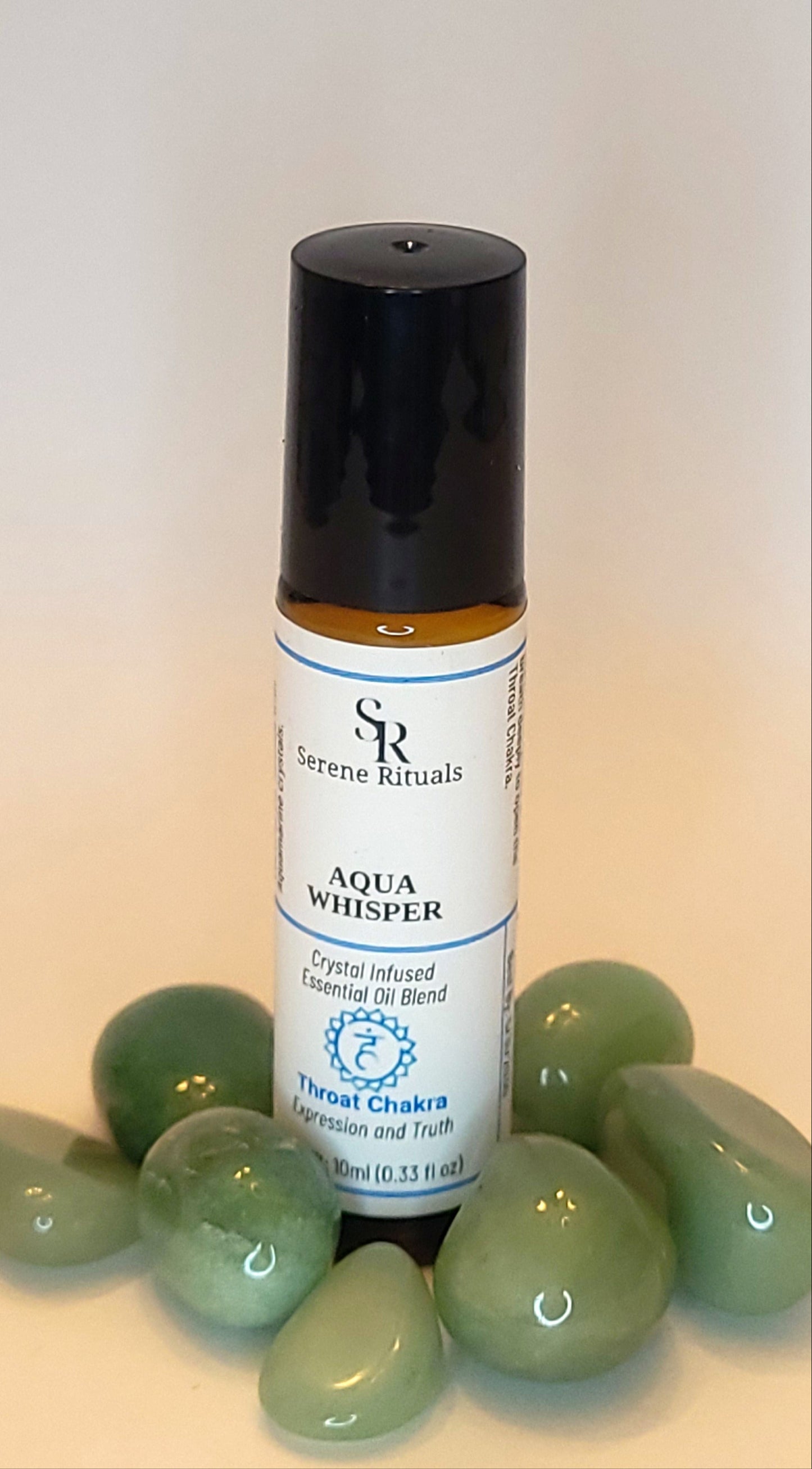 Aqua Whisper essential oil bottle with a label on a light background with Green Aventurine crystals