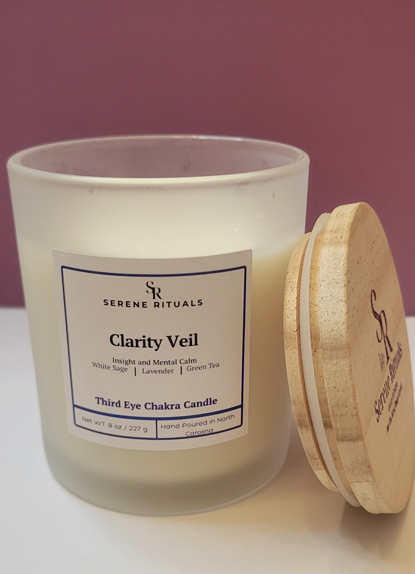 Serene Rituals Clarity Veil candle with wooden lid on a white surface against a purple background