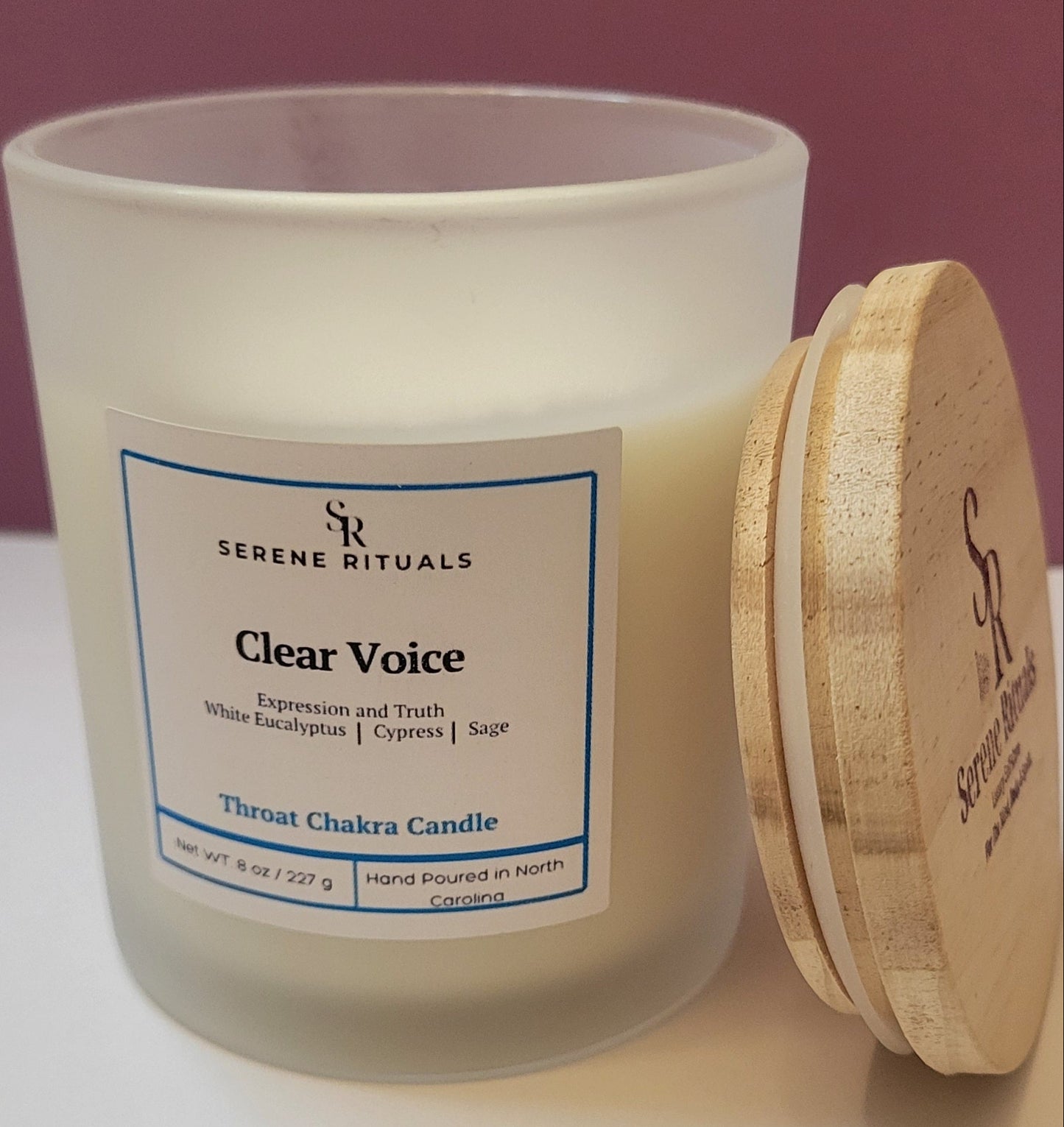 Frosted candle jar with wooden lid and 'Serene Rituals' label on a white surface.