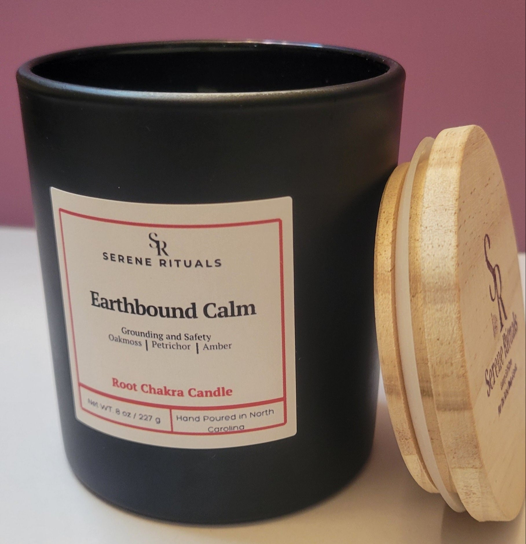 Earthbound Calm candle with a wooden lid and 'Serene Rituals' label on a pink background