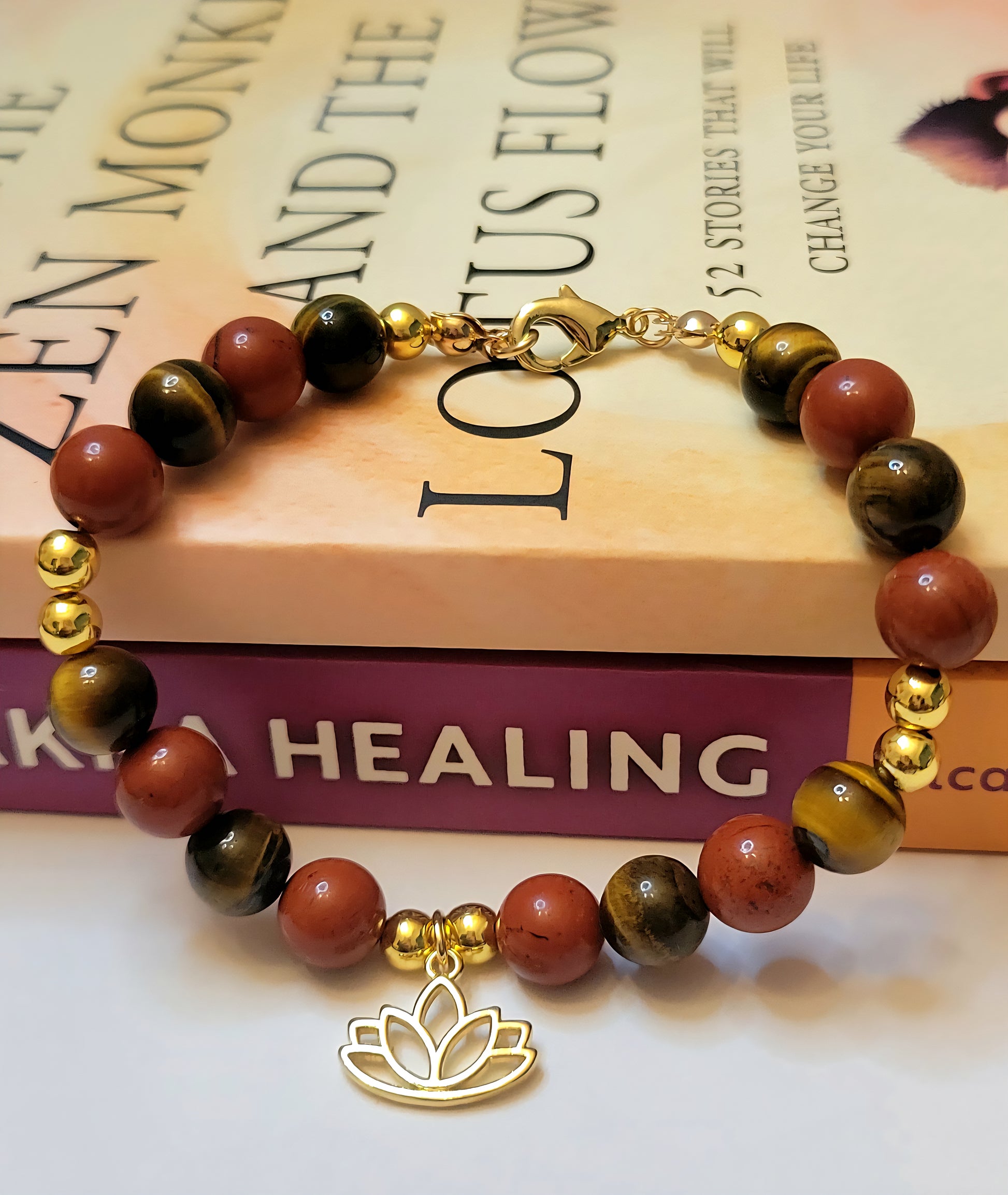 Fearless Strength Bracelet with Tiger's Eye and Red  Jasper beads and gold accents on a book titled 'Healing Lotus Flower'.