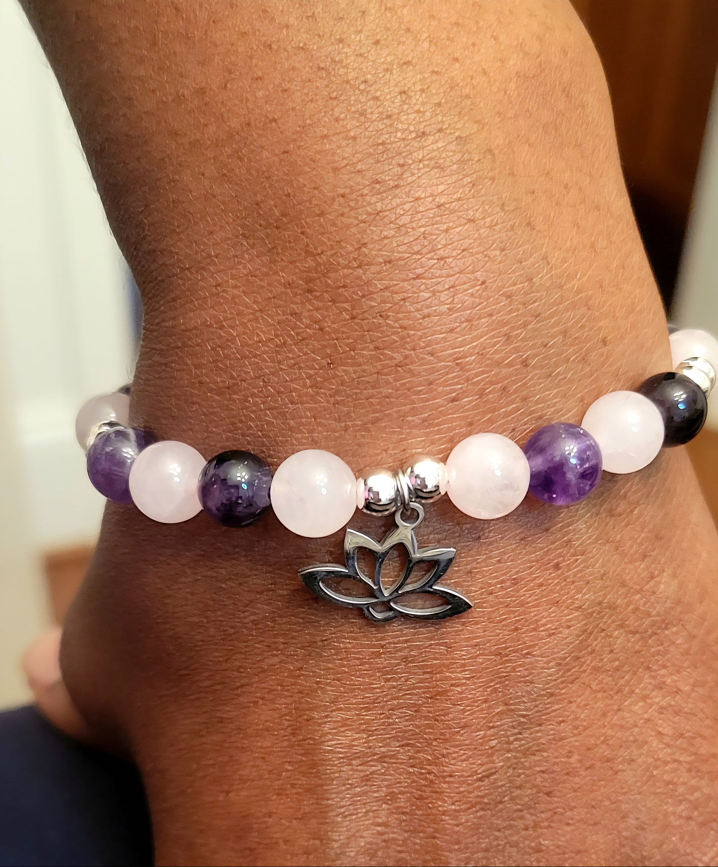 Heart and Soul Bracelet with Amethyst and Rose Quartz beads and a silver lotus charm on a wrist.