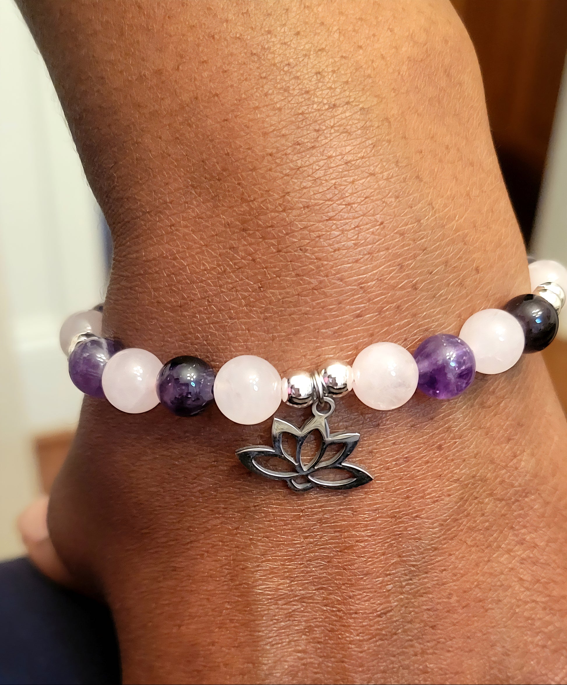 Heart and Soul Bracelet with Amethyst and Rose Quartz beads and a silver lotus charm on a wrist.