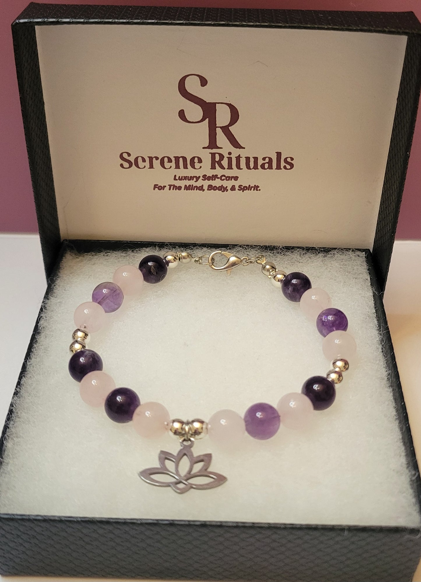 Heart and Soul Bracelet with Amethyst and Rose Quartz beads and a silver lotus flower charm on a 'Serene Rituals' branded box.