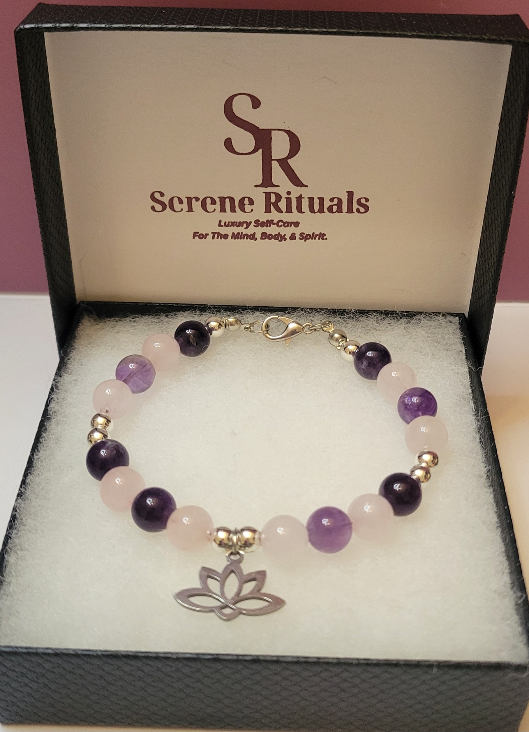 Heart and Soul Bracelet with Amethyst and Rose Quartz beads and a silver lotus flower charm on a 'Serene Rituals' branded box.
