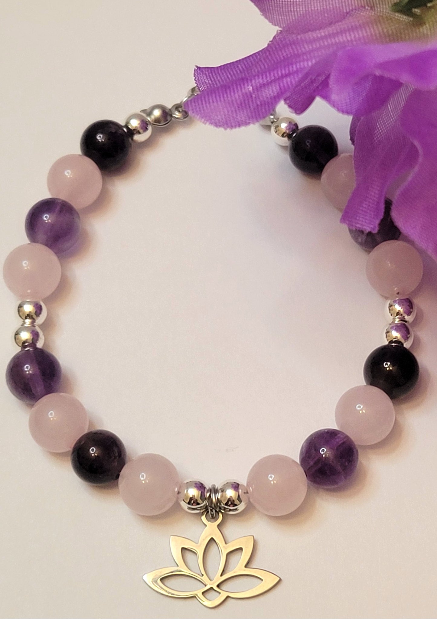 Heart and Soul Bracelet with Amethyst and Rose Quartz beads and a gold lotus charm on a light background