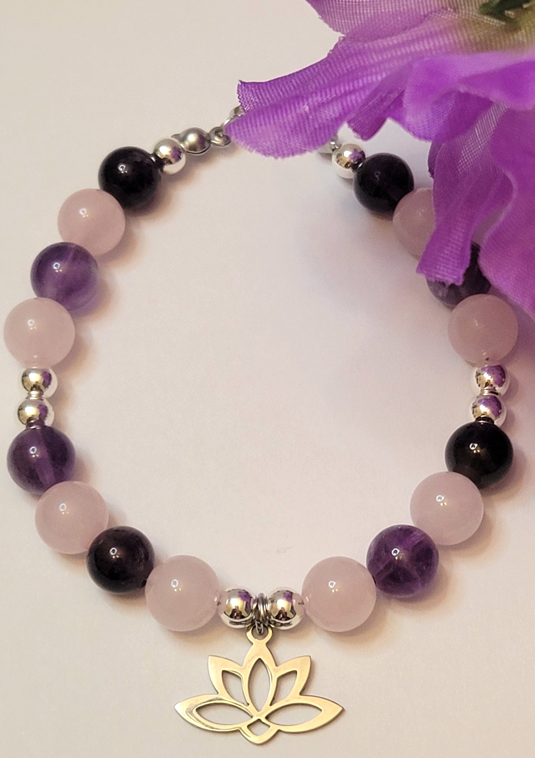 Heart and Soul Bracelet with Amethyst and Rose Quartz beads and a gold lotus charm on a light background