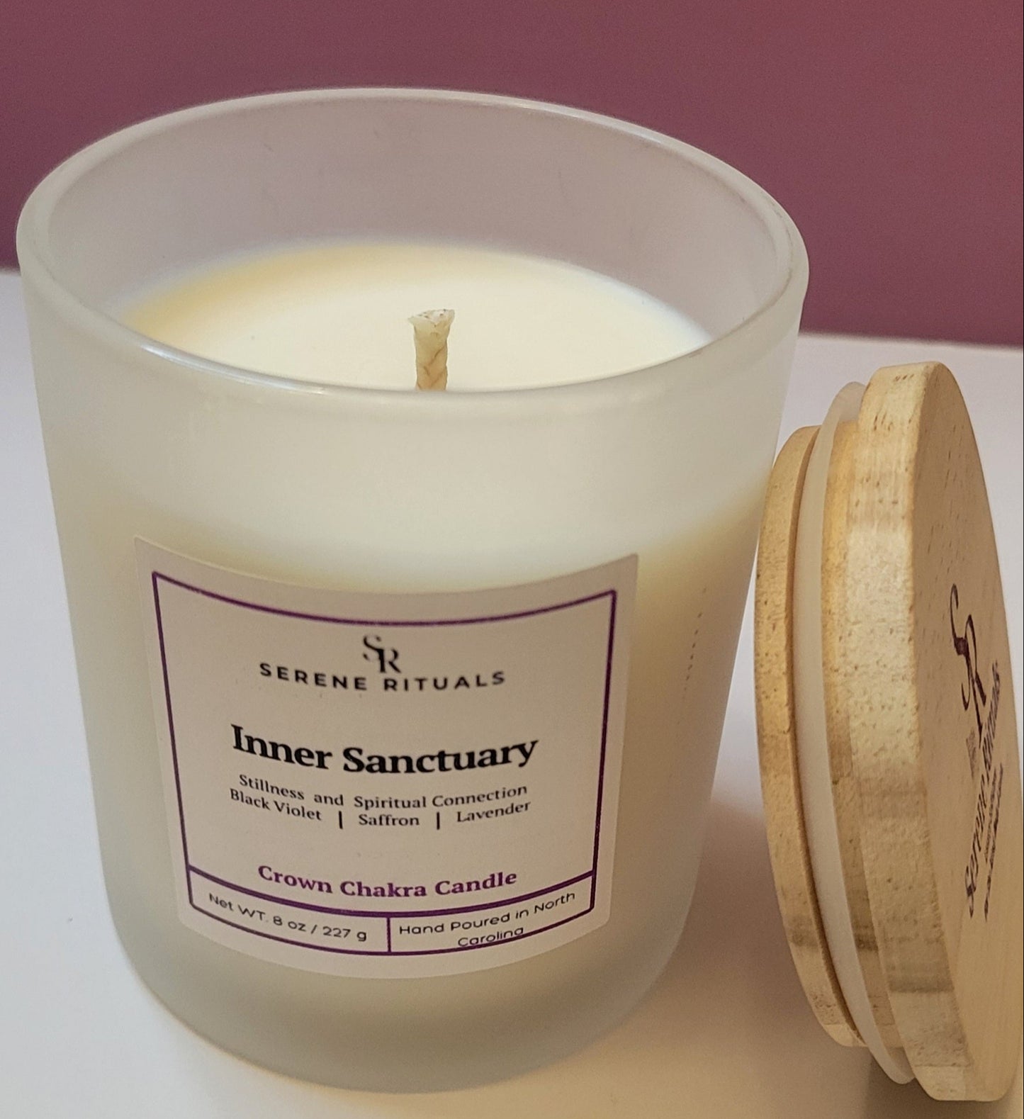 Frosted candle jar with wooden lid labeled 'Inner Sanctuary' by Serene Rituals on a white surface.