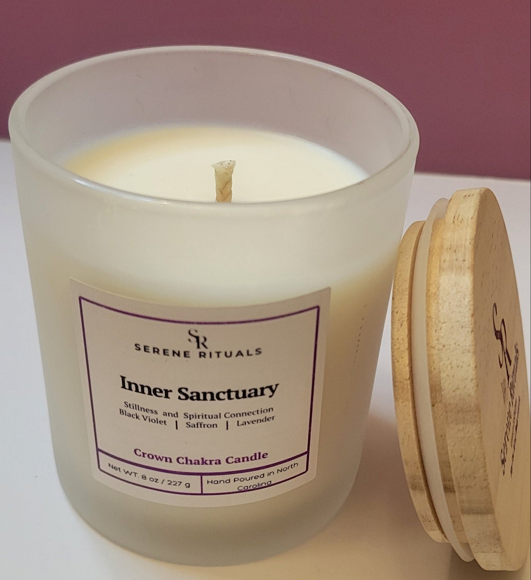 Frosted candle jar with wooden lid labeled 'Inner Sanctuary' by Serene Rituals on a white surface.