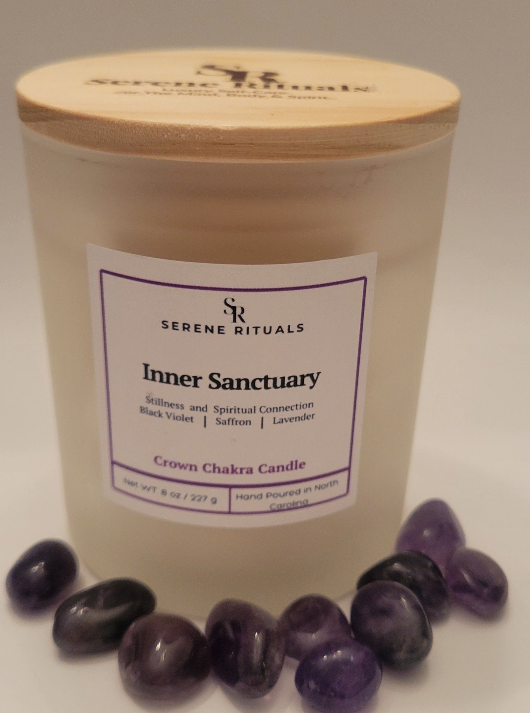 Candle labeled 'Inner Sanctuary' from Serene Rituals with purple stones on a white background