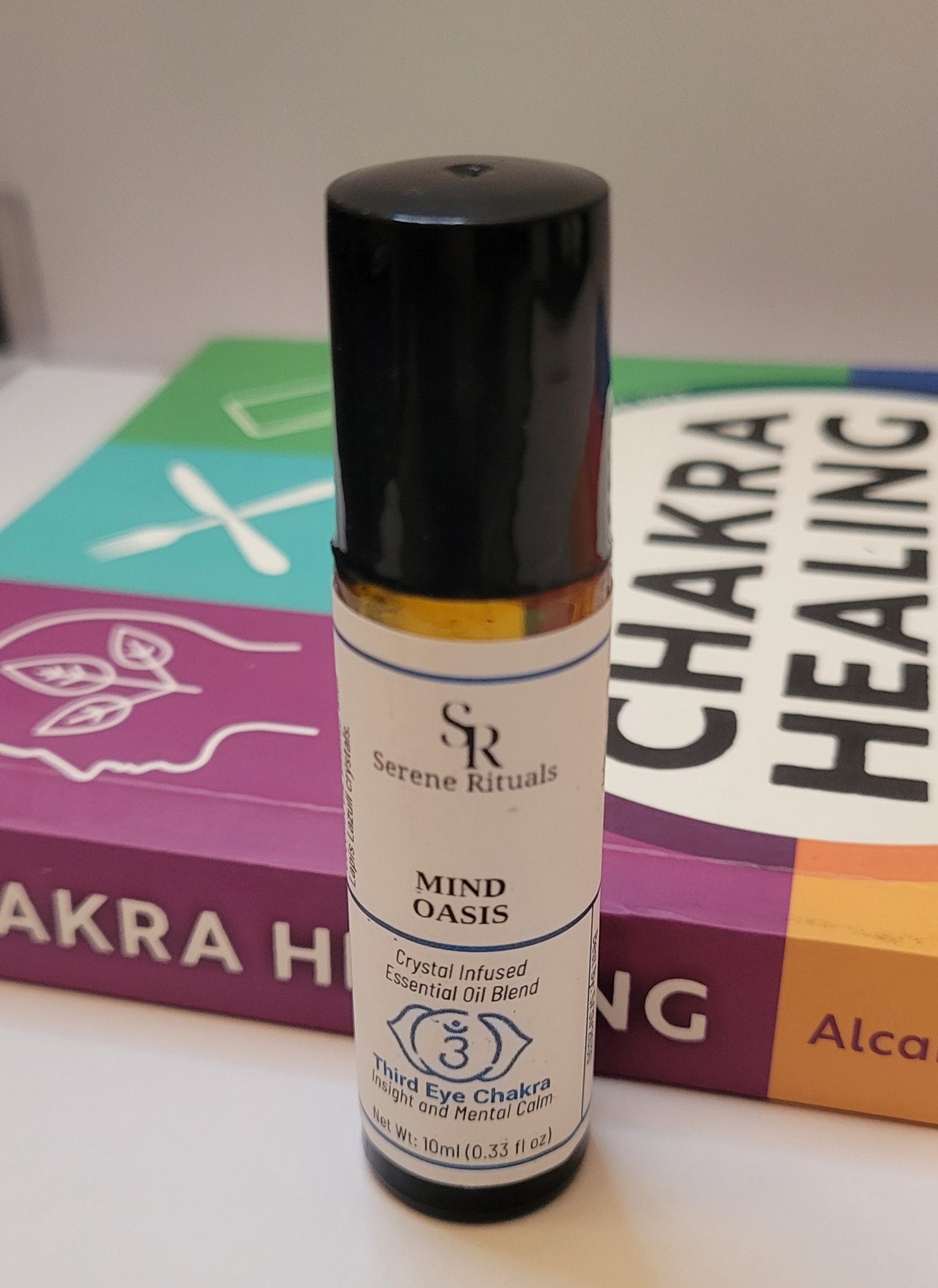 Serene Rituals Mind Oasis essential oil blend bottle with a Chakra Healing book in the background