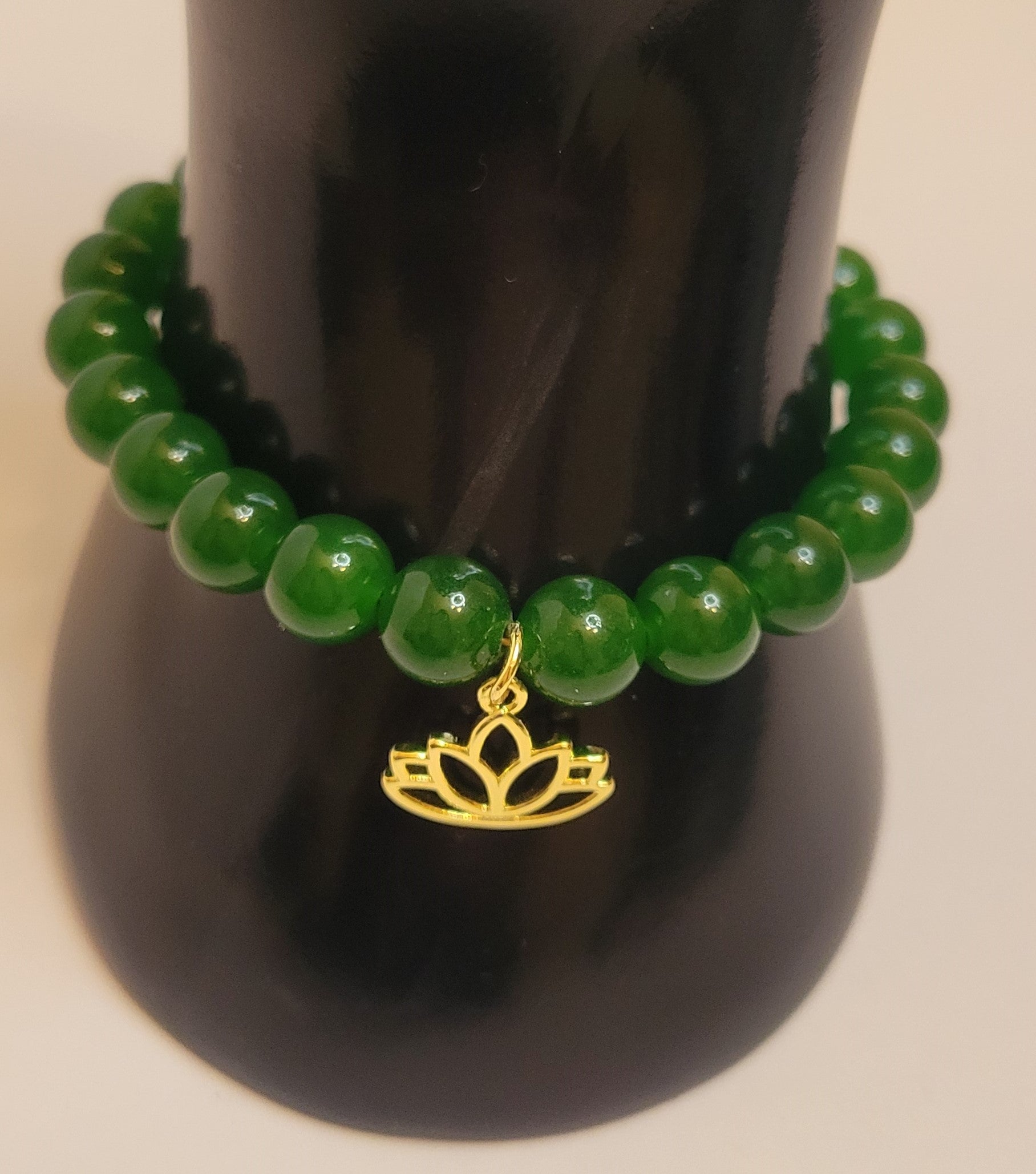 A handcrafted bracelet featuring polished Taiwan Green Nephrite Jade beads, gold-filled lotus charm and clasp. The design embodies balance, harmony, and grounding energy, styled as part of Serene Rituals’ luxury gemstone collection.