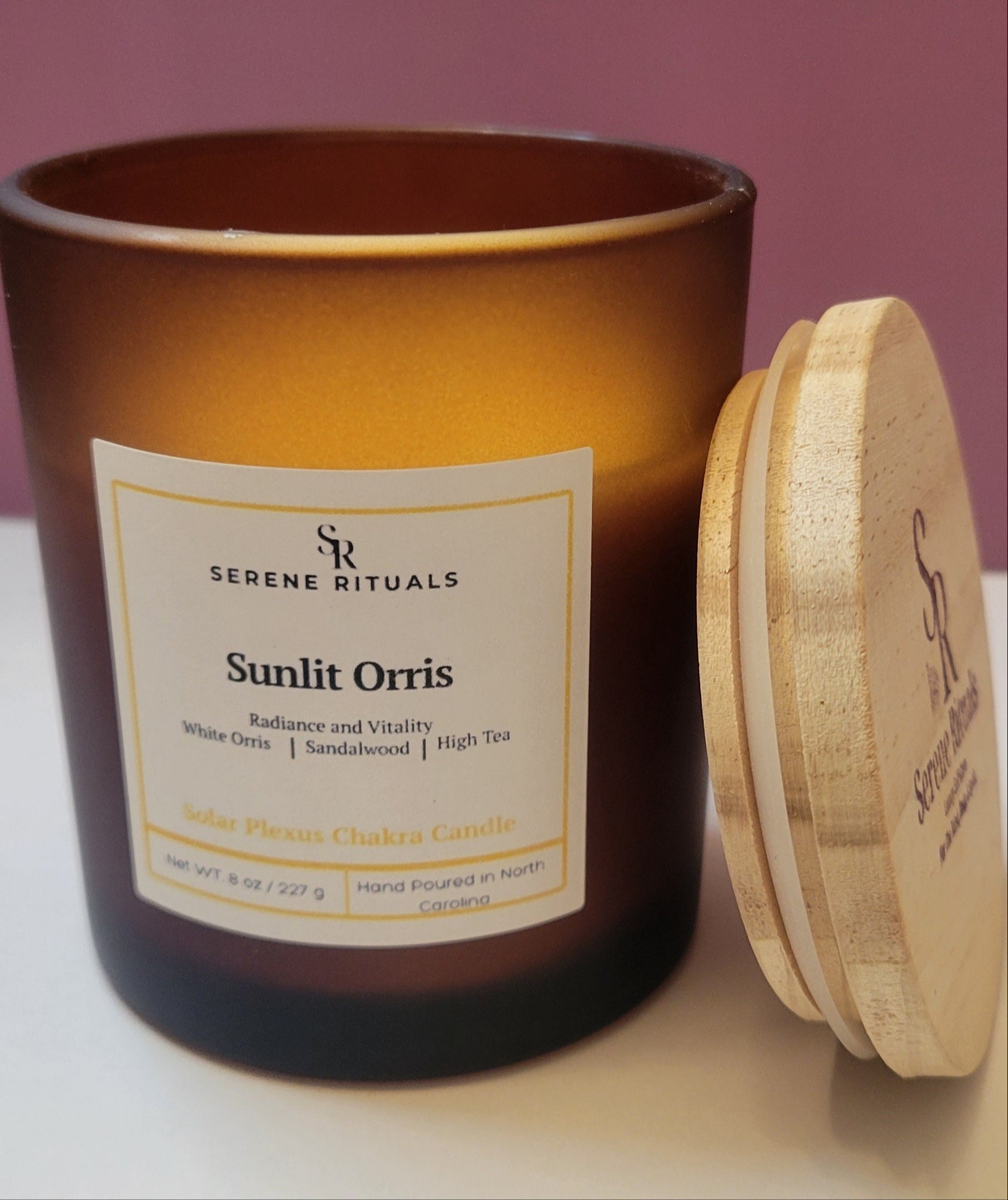 Serene Rituals Sunlit Orris candle with wooden lid on a pink background